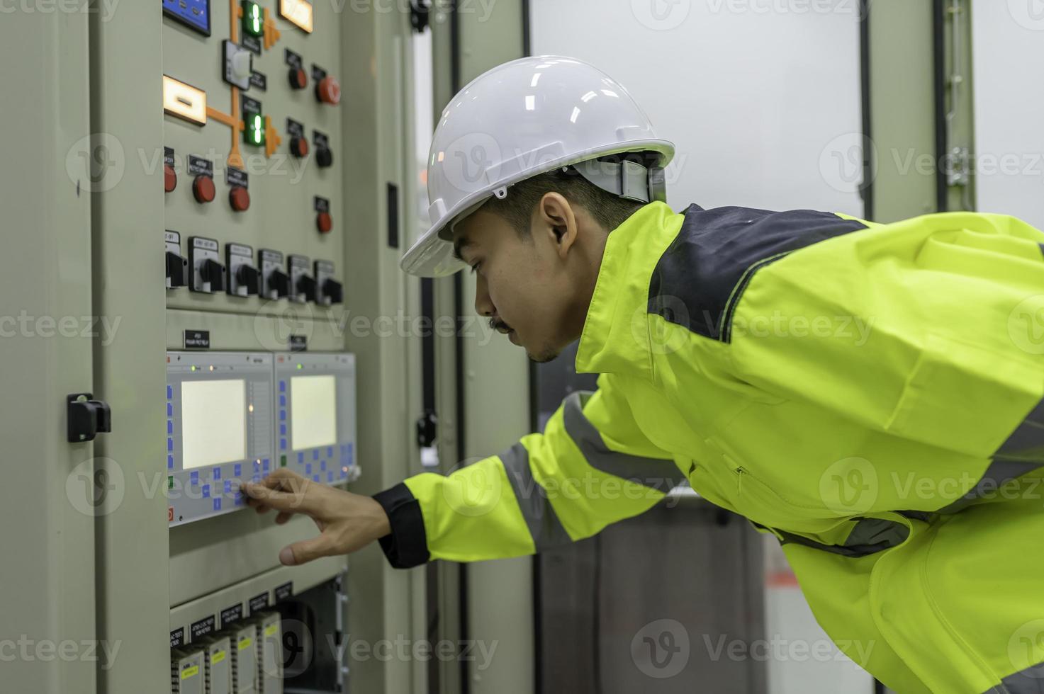 homem engenheiro elétrico verificando a tensão no gabinete de distribuição de energia na sala de controle, manutenção preventiva anualmente, eletricista tailandês trabalhando na empresa foto