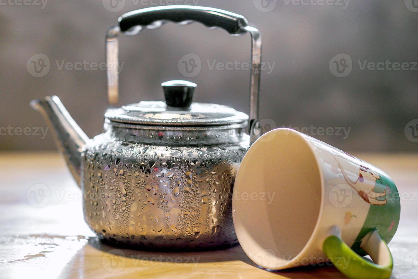gotas em a chaleira e cerâmico café copo em de madeira mesa e borrado background. foto