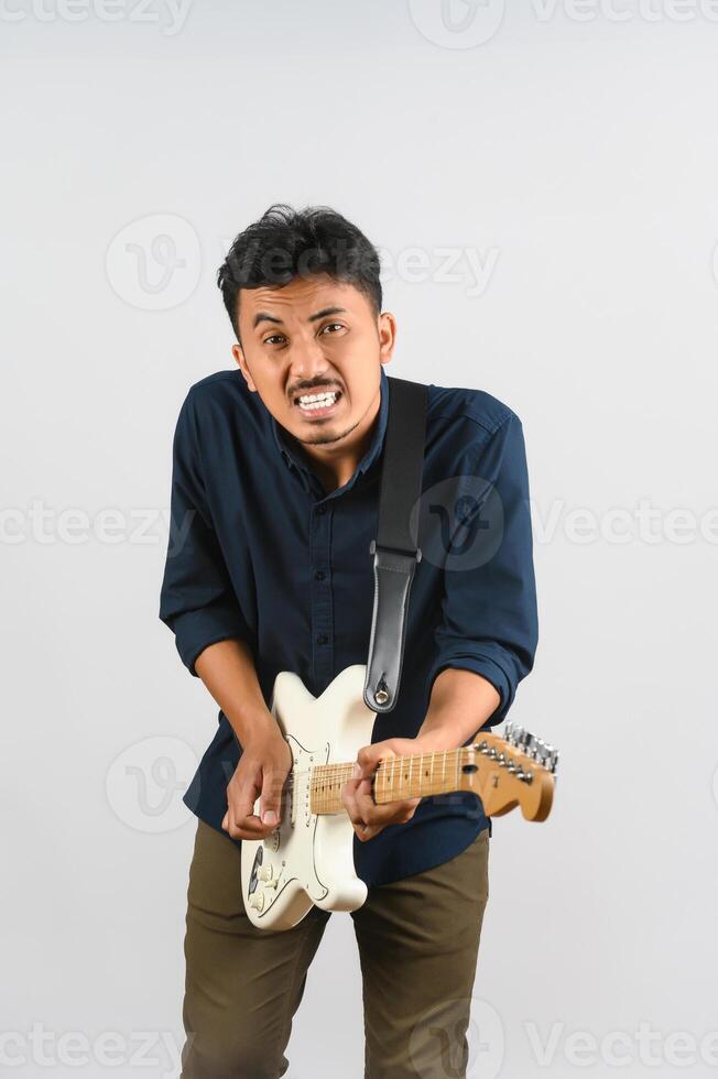 retrato de jovem asiático na camisa azul com guitarra eletrônica isolada no fundo branco foto