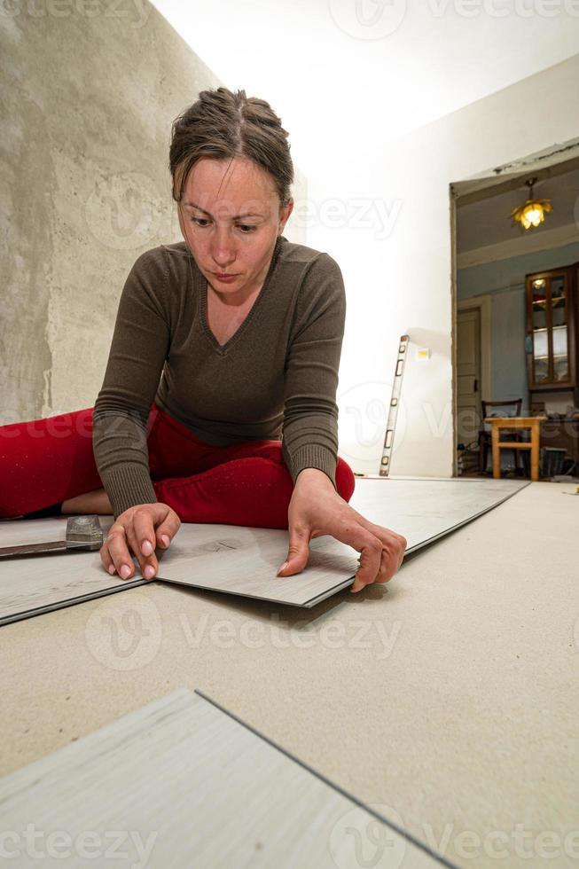 instalando uma quartzo vinil chão, uma mulher executa instalação trabalhar. foto