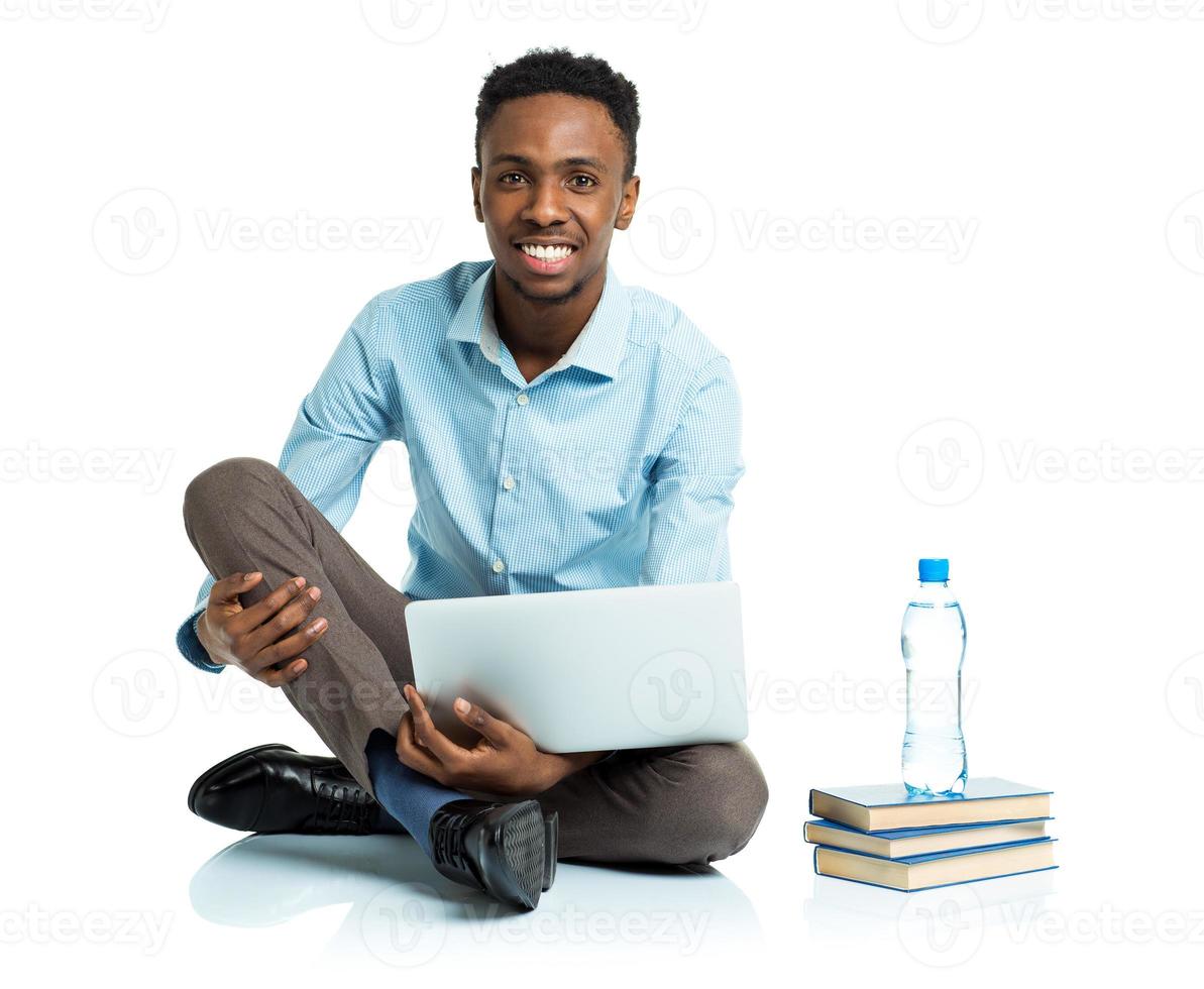 feliz africano americano Faculdade aluna com computador portátil, livros e garrafa do água sentado em branco foto