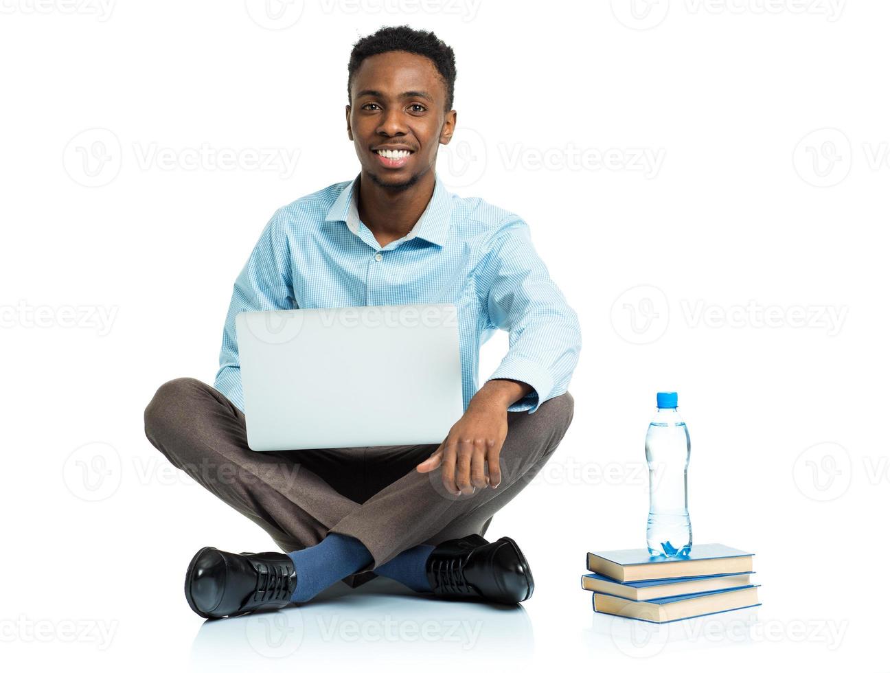 feliz africano americano Faculdade aluna sentado com computador portátil em branco fundo foto