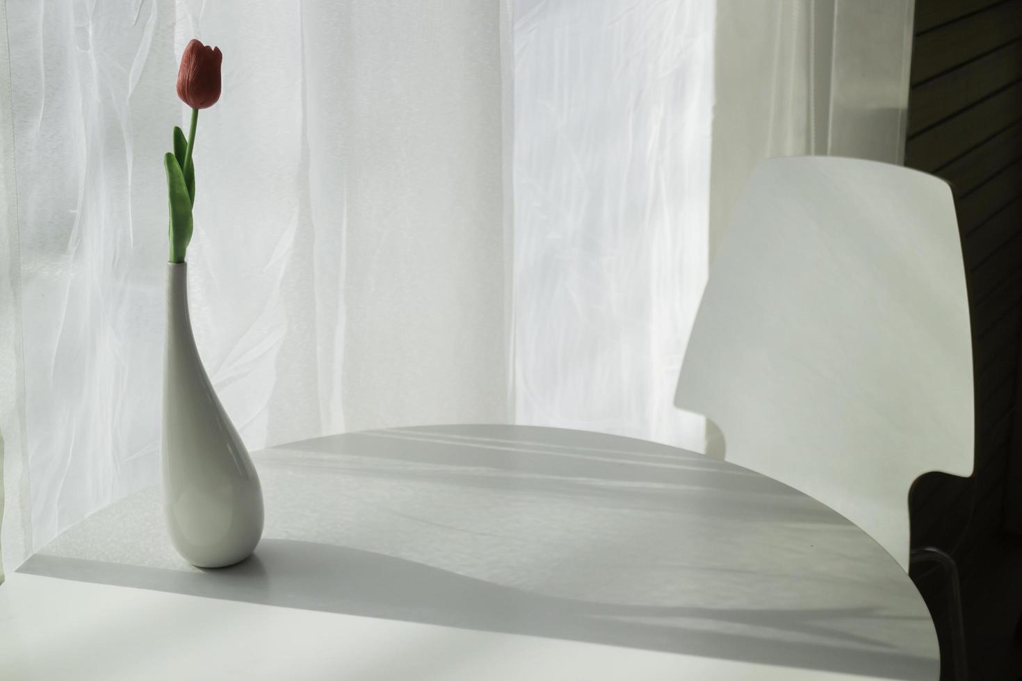 vaso de flores com luz forte da janela foto