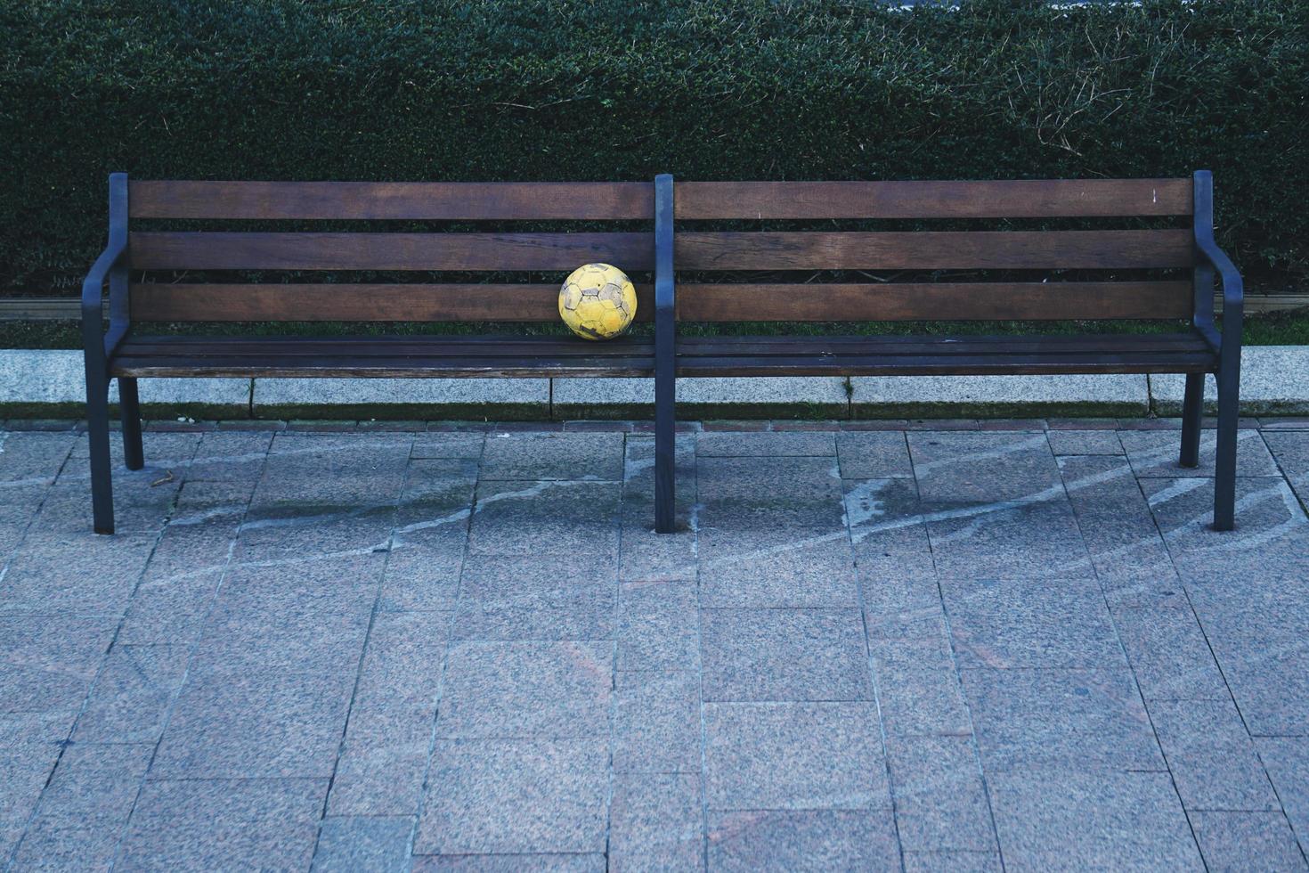 bola de futebol em um banco de madeira na rua foto