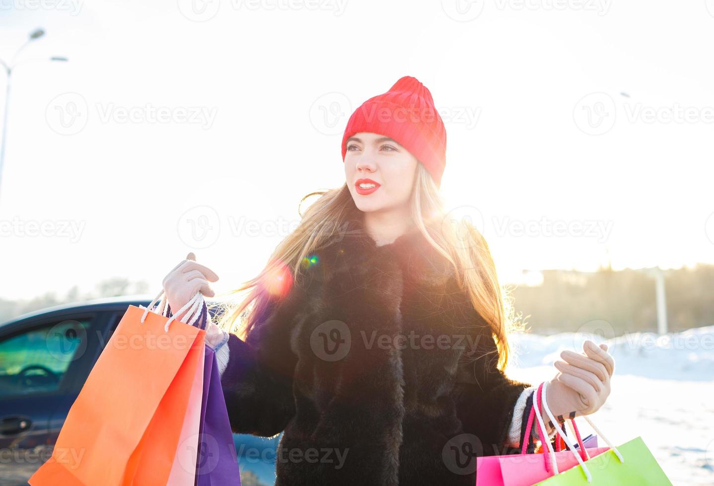 sorridente caucasiano mulher segurando dela compras saco perto a carro foto