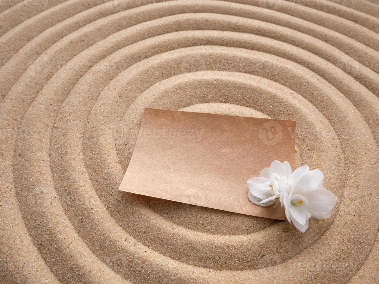 carta dentro a areia. construir papel com uma branco flor em a textura do mar areia. conceito do uma de praia feriado foto