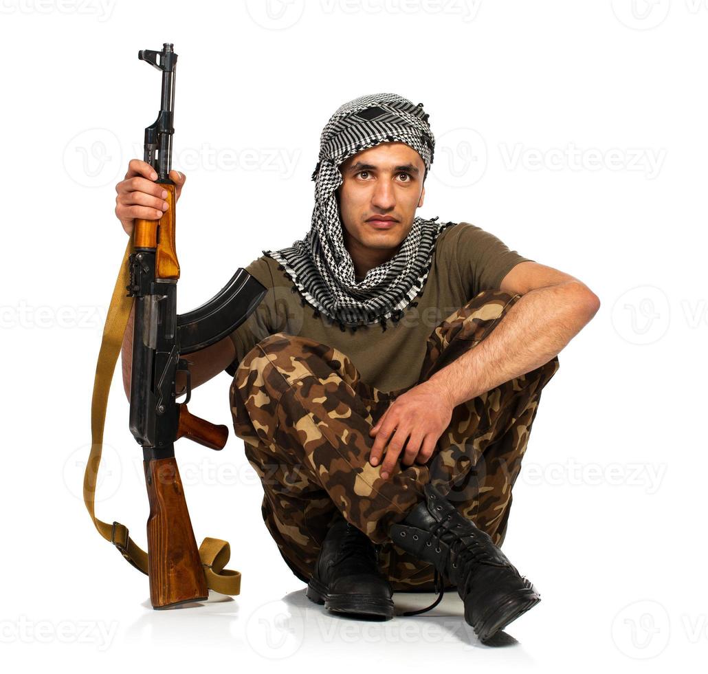 árabe nacionalidade dentro camuflar terno e keffiyeh com automático arma de fogo em branco fundo foto