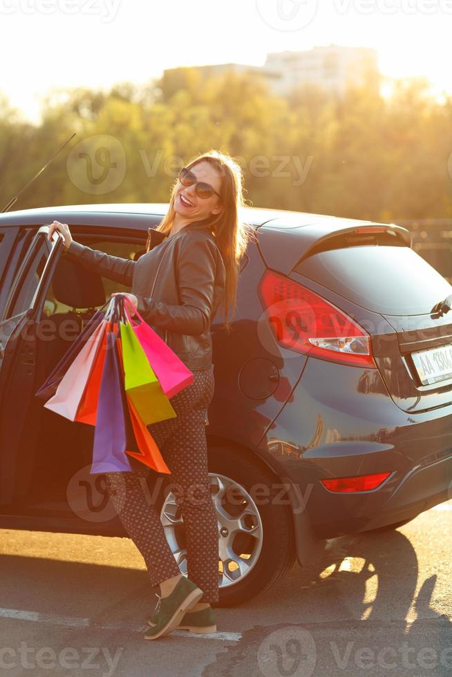 sorridente caucasiano mulher colocando dela compras bolsas para dentro a carro foto