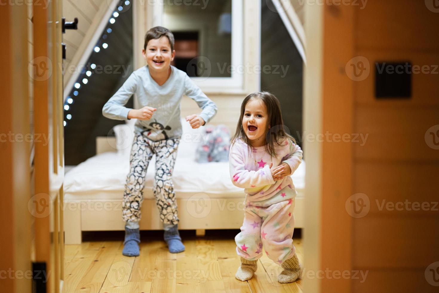 crianças dentro suave caloroso pijamas jogando às de madeira cabine lar. conceito do infância, lazer atividade, felicidade. irmão e irmã tendo Diversão e jogando junto. foto