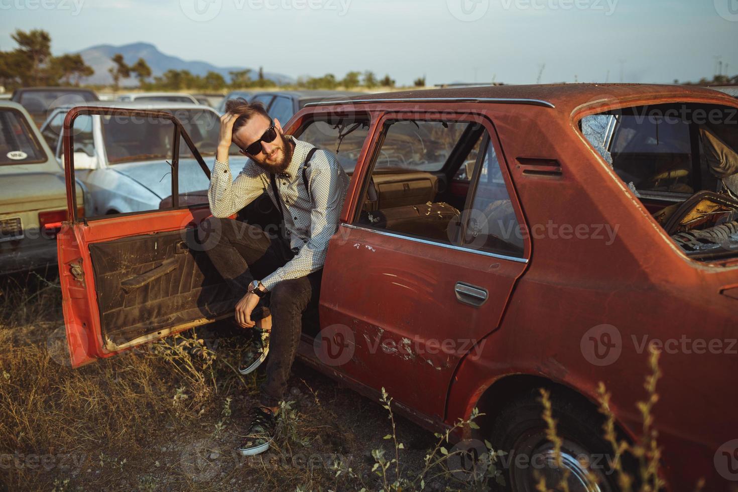 jovem bonito à moda homem, vestindo camisa e gravata-borboleta com velho carros foto