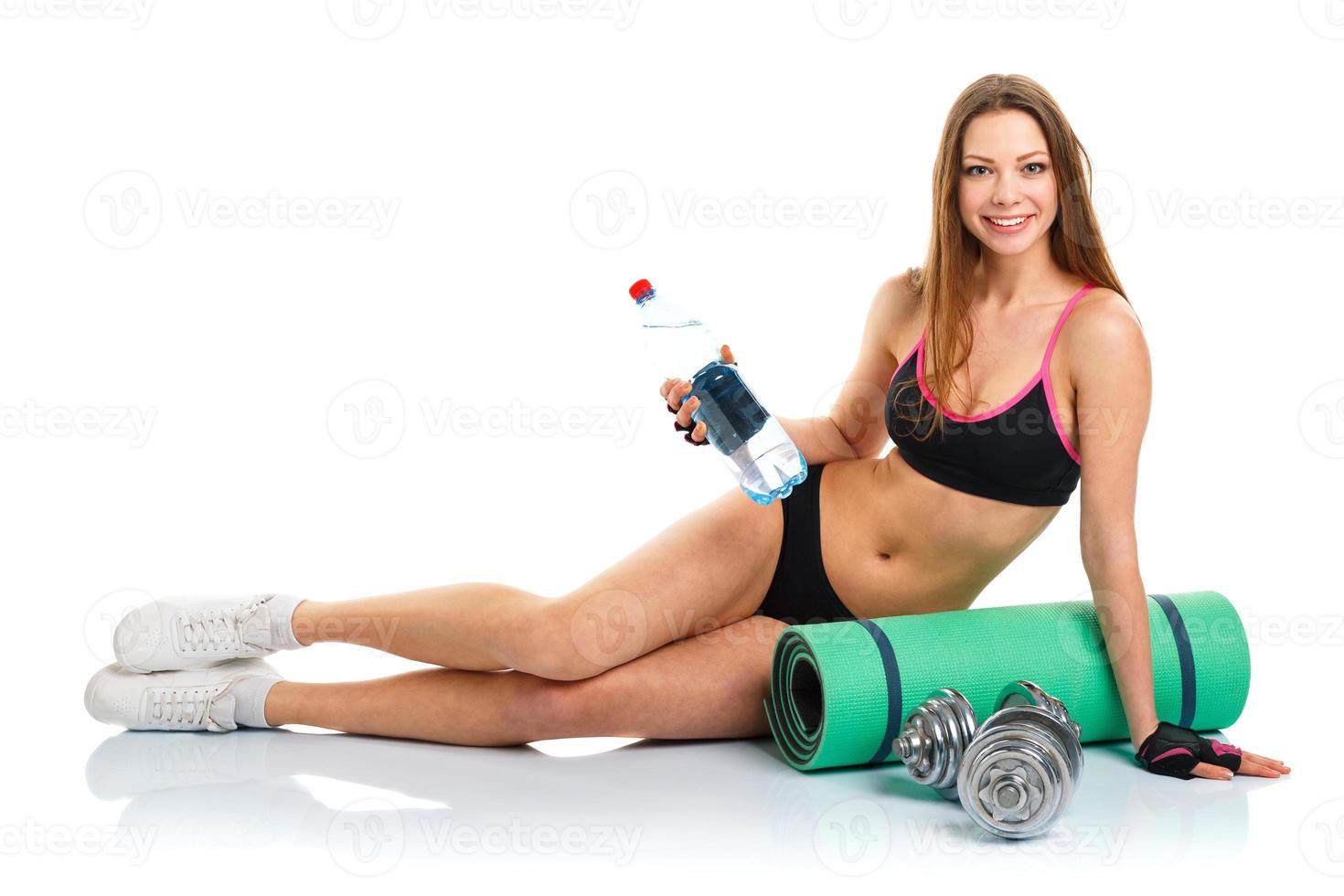 lindo esporte mulher com halteres, garrafa do água e esteira para ginástica foto