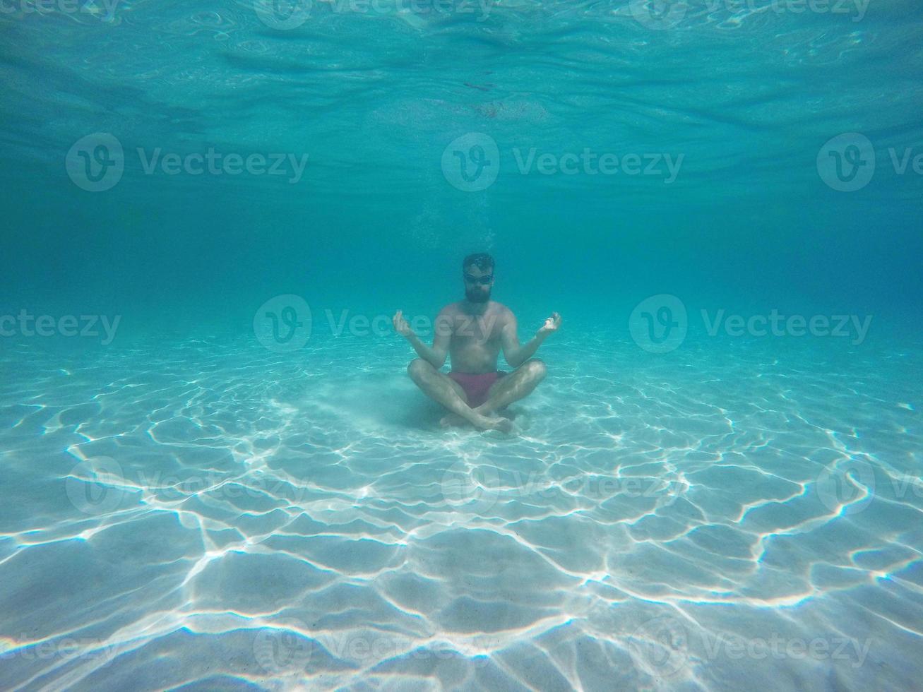 barba homem com óculos dentro a lótus posição meditando debaixo água foto