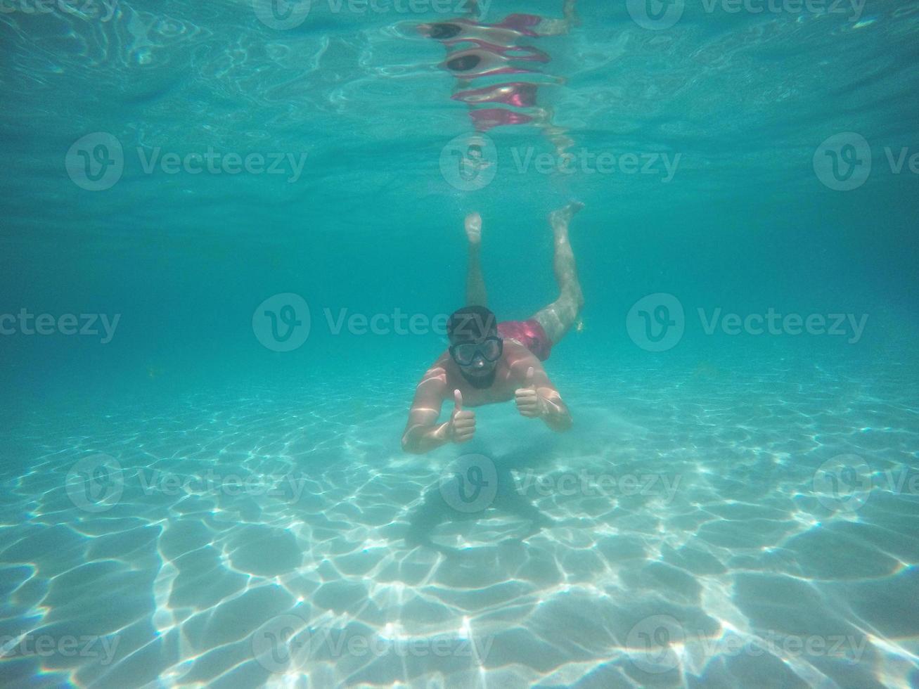 homem dentro óculos com polegares acima mergulho embaixo da agua foto