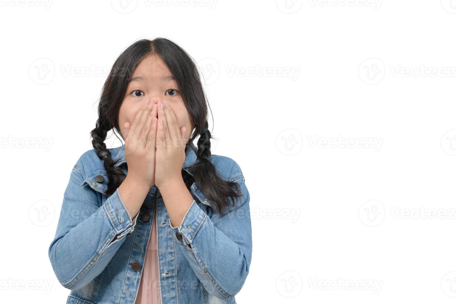 surpreso pequeno menina vestindo jeans Jaqueta cobertura dela boca e olhando às Câmera foto