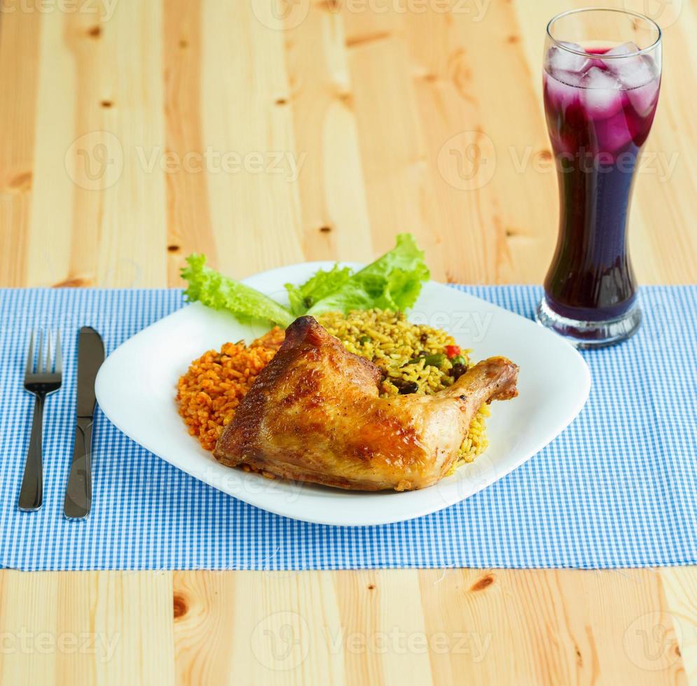 pratos a partir de frango coxa com arroz e alface e uma vidro do suco com gelo foto