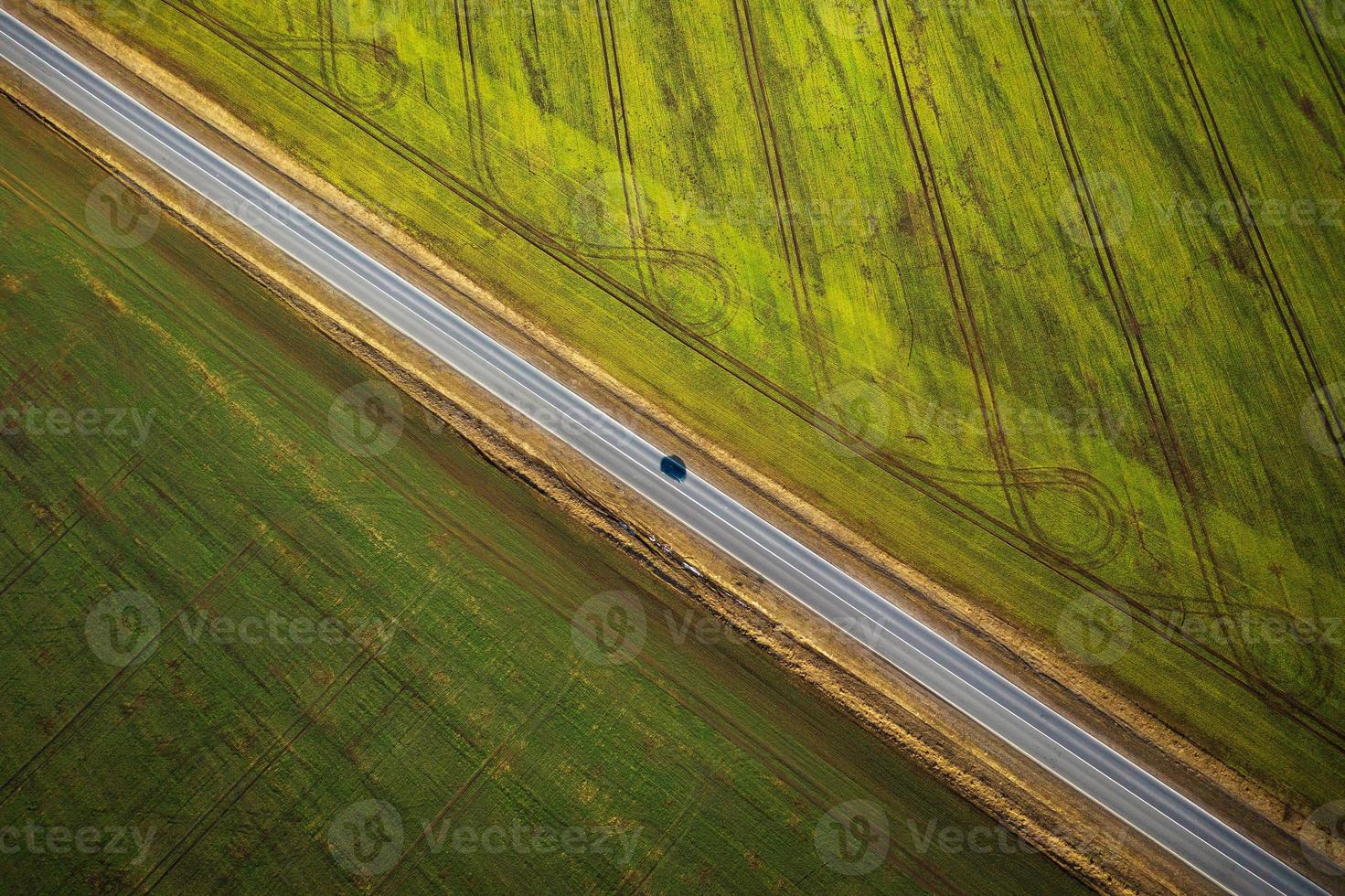 Visão a partir de a altura em a carro dirigindo ao longo uma rural estrada entre dois Campos foto