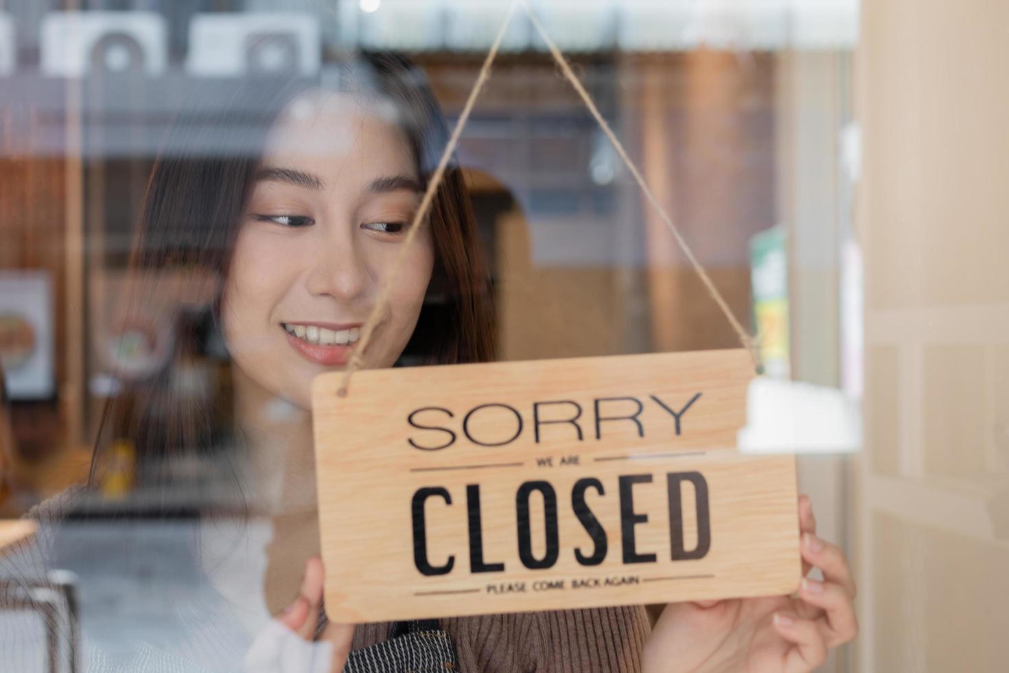 bonita ásia jovem proprietário varejo, café fazer compras mulher girando placa borda para fechadas depois de acabado trabalhar, trabalho e proteção para pandemia do coronavírus. fechar loja vencimento para confinamento, quarentena do covid. foto