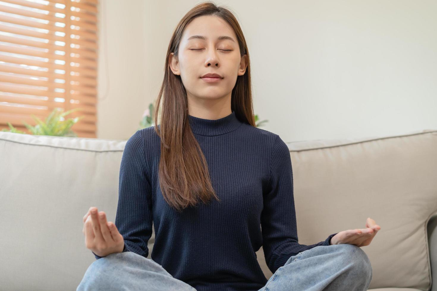 lindo ásia jovem mulher, menina mãos dentro calma pose sentado prática meditando dentro lótus posição em sofá às lar, meditação, exercício para bem-estar, saudável Cuidado. relaxamento, feliz lazer pessoas. foto