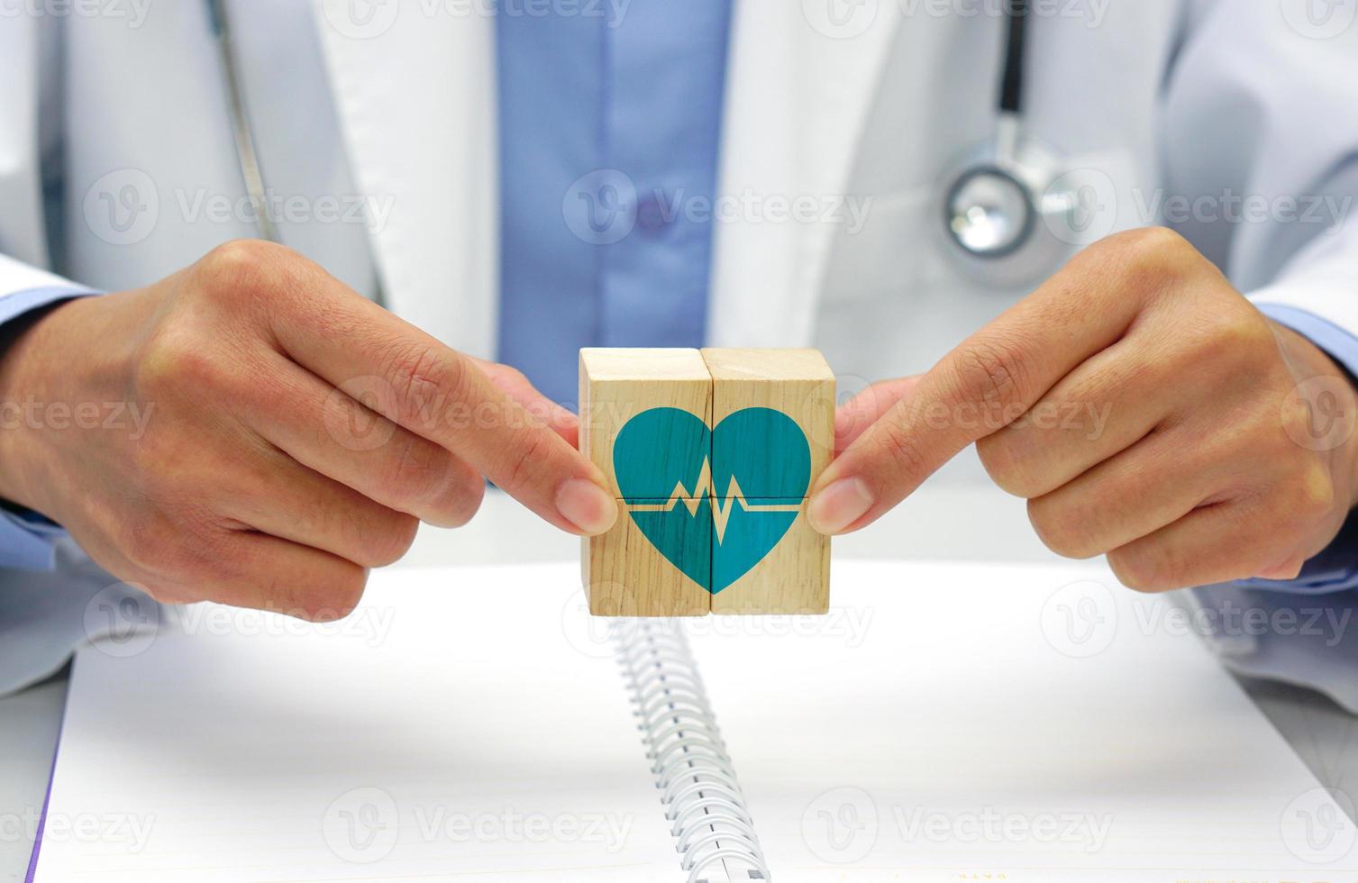 mão segurando uma de madeira quadra cubo com cuidados de saúde médico símbolo, coração taxa ícone. médico e saúde conceito. foto