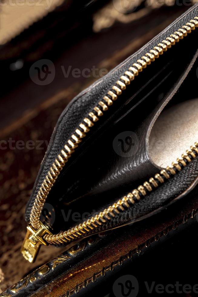 couro carteira com uma dourado zíper fechar-se em uma Sombrio fundo. foto