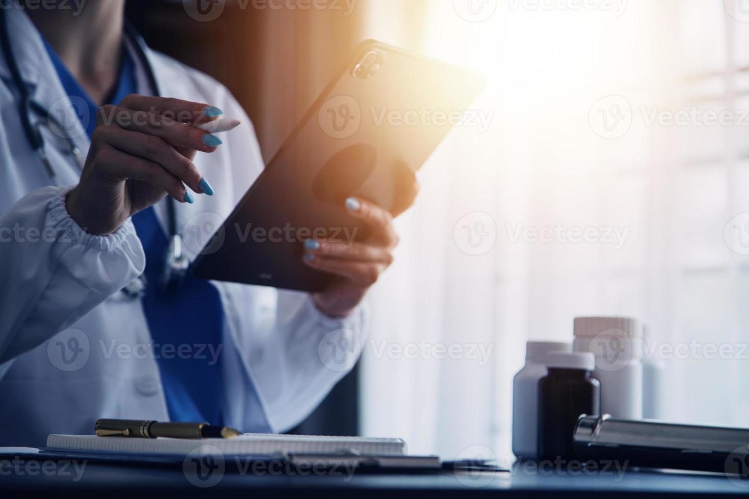 médico trabalhando com computador portátil computador e escrevendo em papelada. hospital fundo. foto