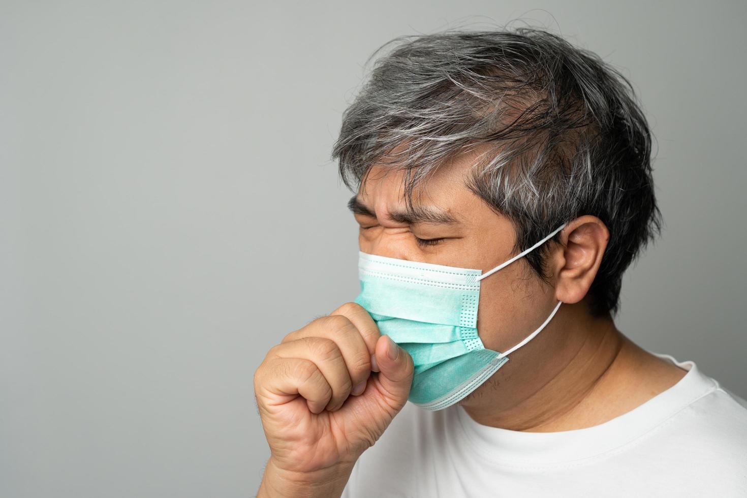 homem asiático doente usando uma máscara facial médica e tossindo e cobrindo a boca com a mão. conceito de proteção coronavírus pandêmico e doenças respiratórias foto