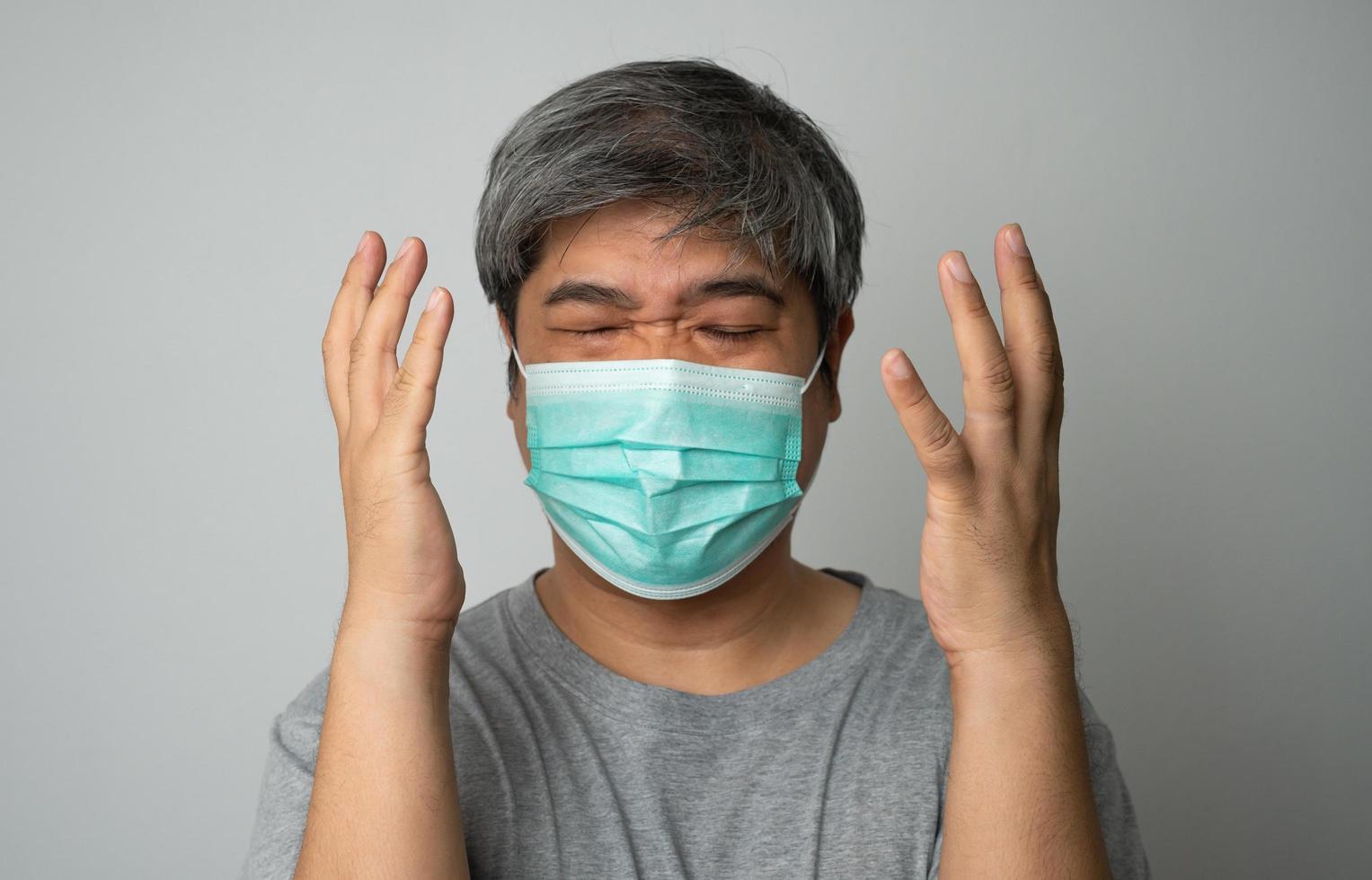 homem asiático doente usando uma máscara facial médica e dor no ombro e estresse. conceito de proteção coronavírus pandêmico e doenças respiratórias foto