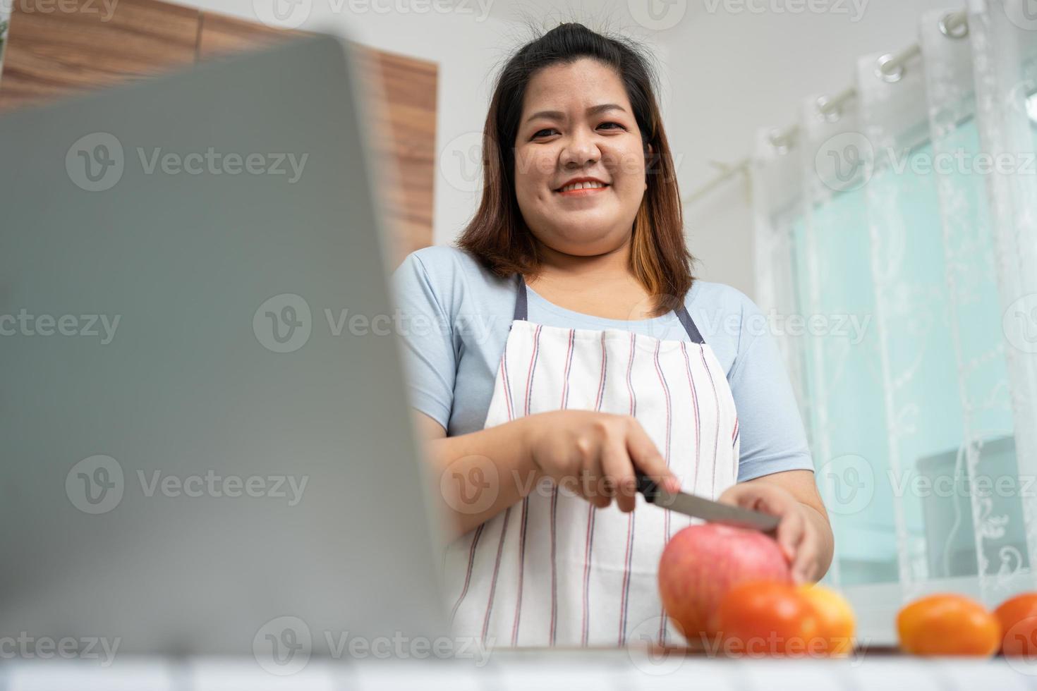 grávida asiática aprenda a cozinhar refeições saudáveis da internet na cozinha, mulheres gordas preparam uma salada de legumes para dieta alimentar e perdem peso. conceito de alimentação saudável foto