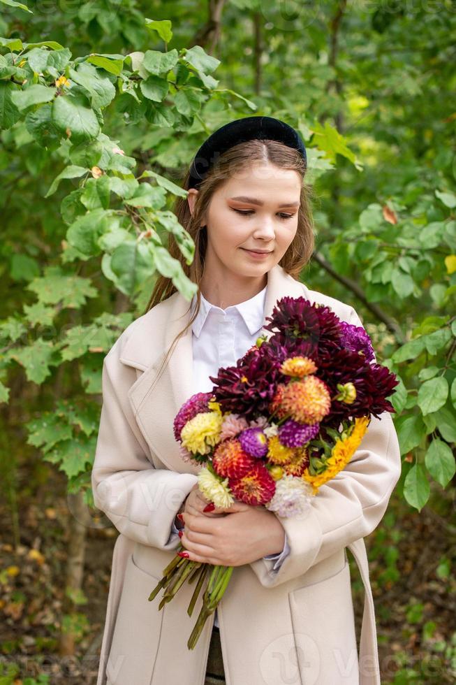uma fofa menina com uma Preto arco de cabelo e grandes cabelo detém uma ramalhete do outono flores foto