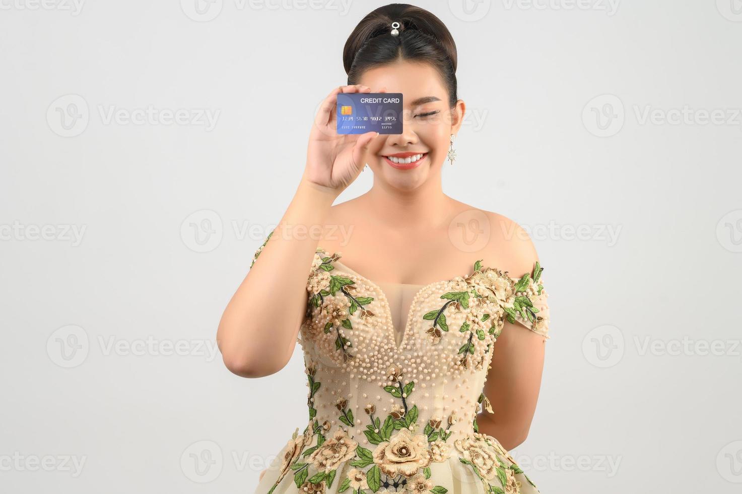 jovem noiva linda asiática postando com cartão de crédito e pincel de beleza na mão foto