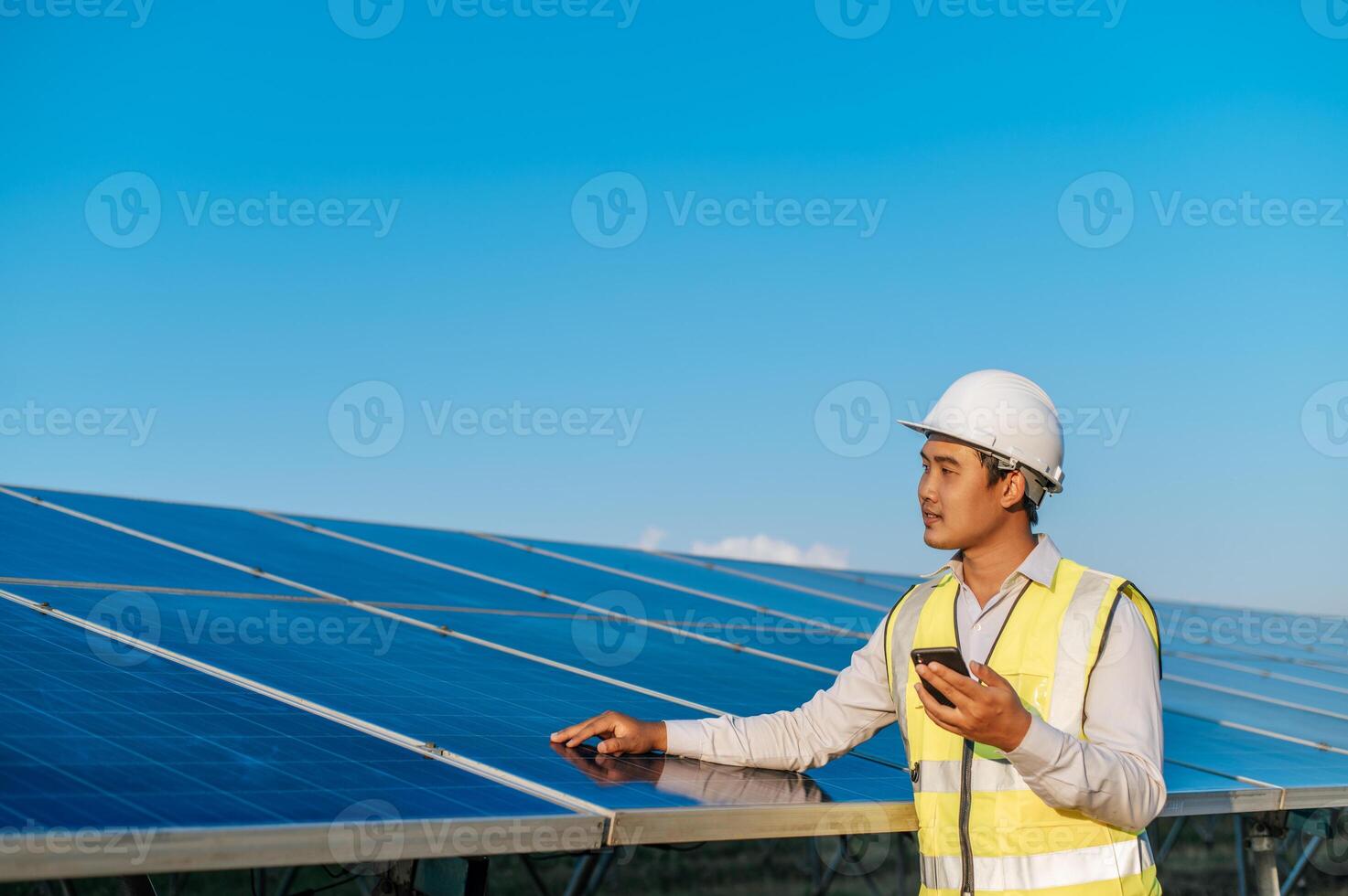 jovem engenheiro usa smartphone enquanto trabalha na fazenda solar foto