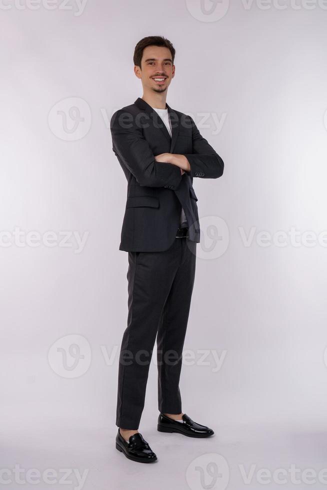 retrato do jovem empresário bonito vestindo terno de pé com os braços cruzados com isolado no fundo branco do estúdio foto
