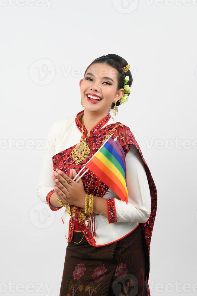 retrato do jovem mulher dentro tailandês nordeste tradicional roupas segurando arco Iris bandeira foto
