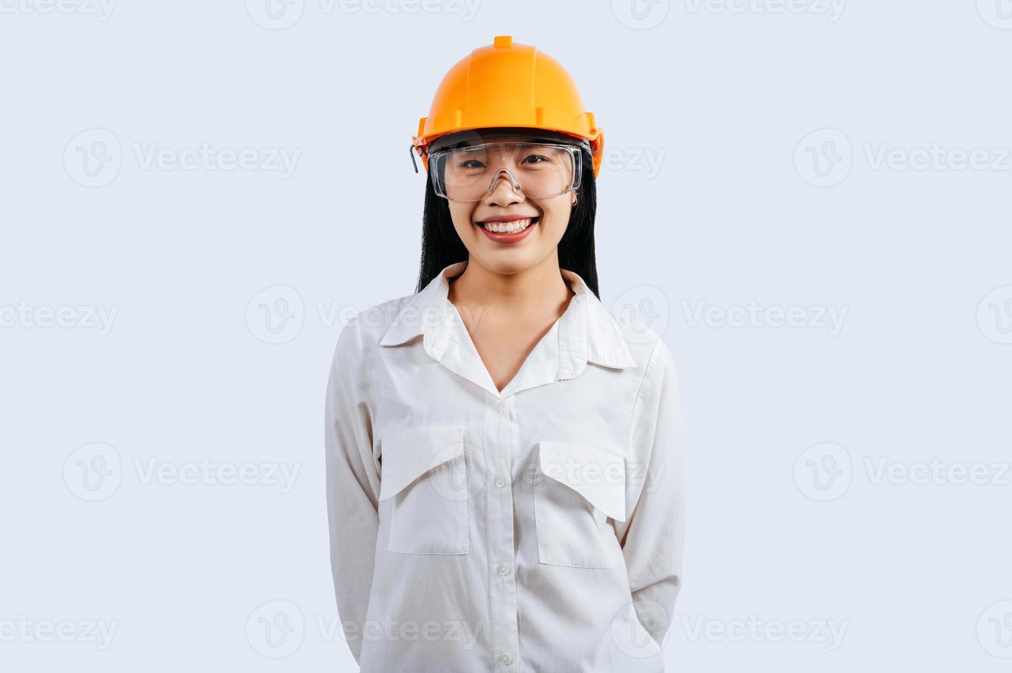 jovem fêmea engenheiro vestindo amarelo capacete ficar de pé com encantador sorrir postura foto