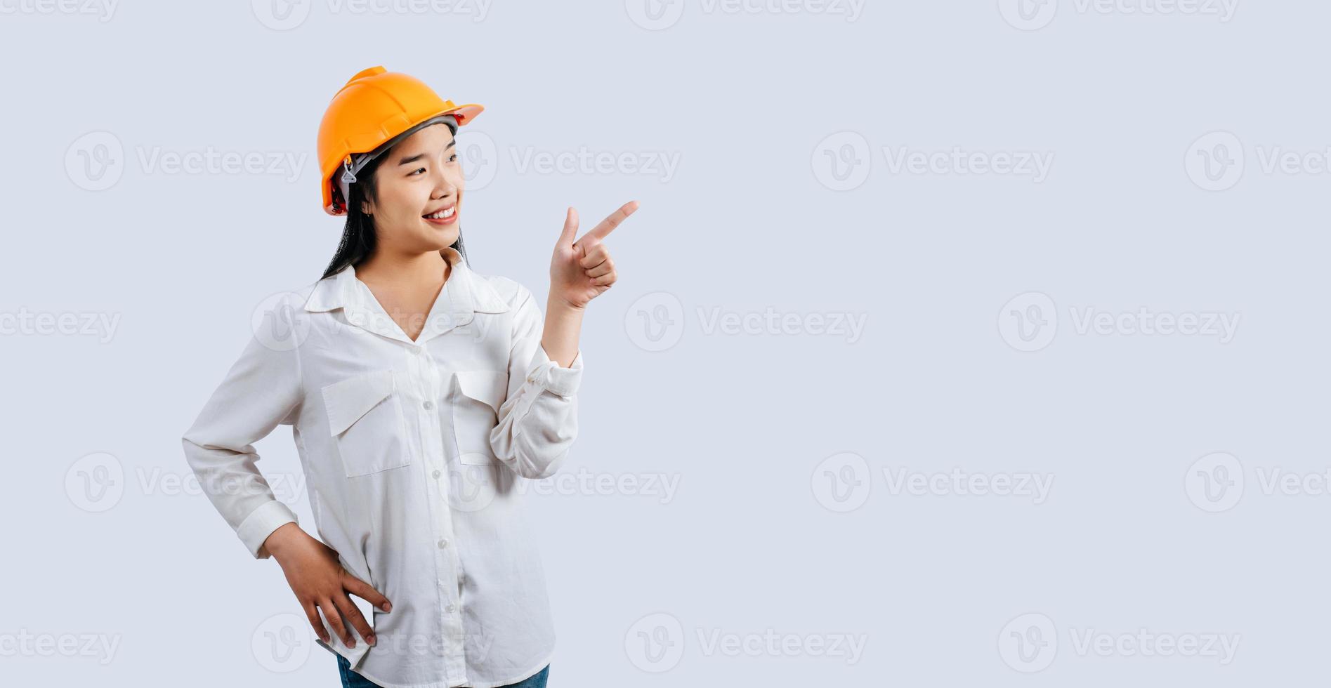 jovem ásia engenheiro fêmea em pé com ponto dedo postura foto
