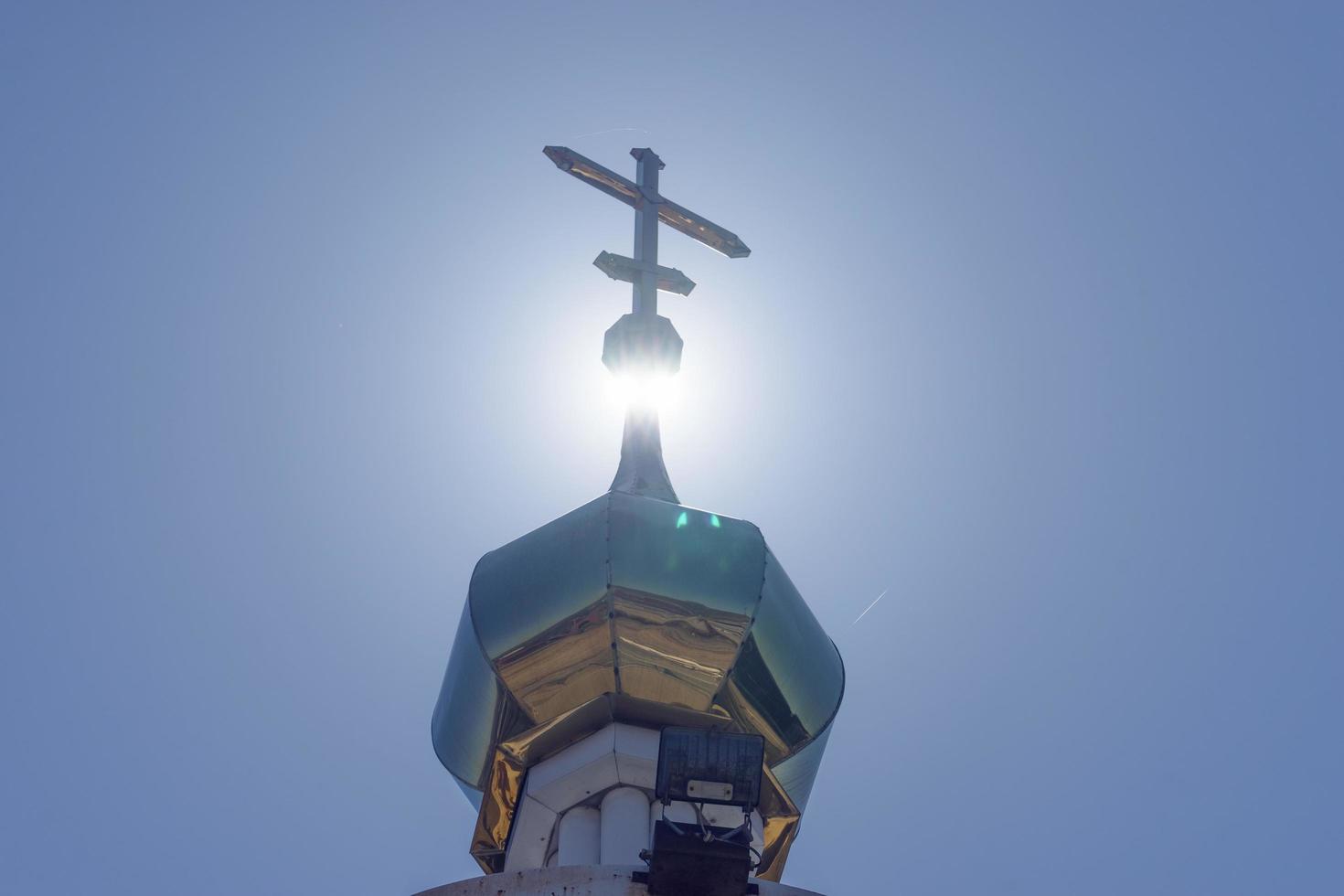 cúpula dourada em uma torre iluminada por trás com um céu azul claro em vladivostok, Rússia foto