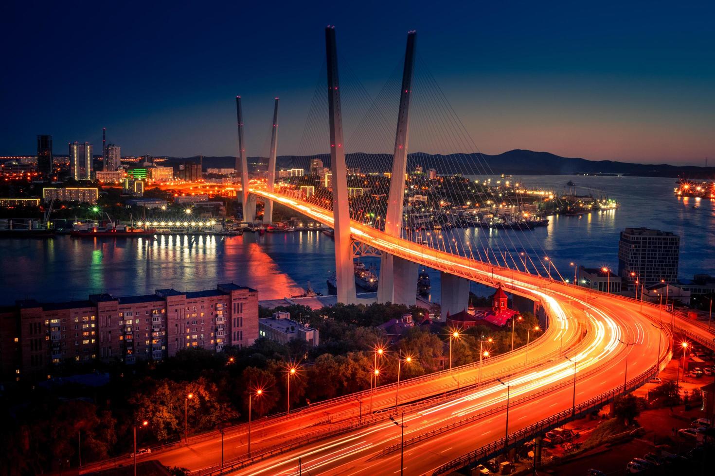 paisagem urbana com as luzes desfocadas dos carros na ponte dourada ao pôr do sol em Vladivostok, Rússia foto