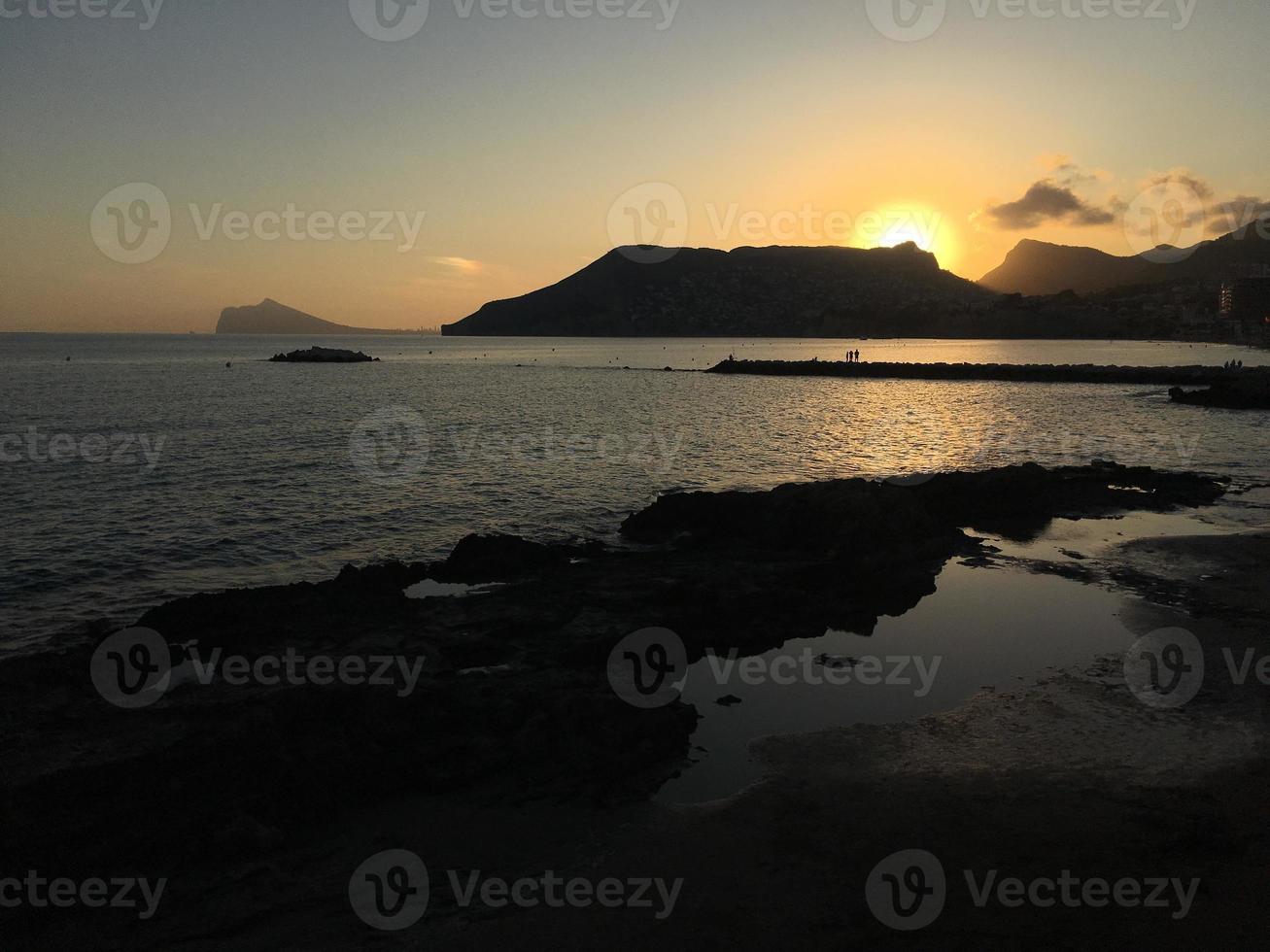 praia mediterrânea sem pessoas ao pôr do sol em calpe, alicante foto