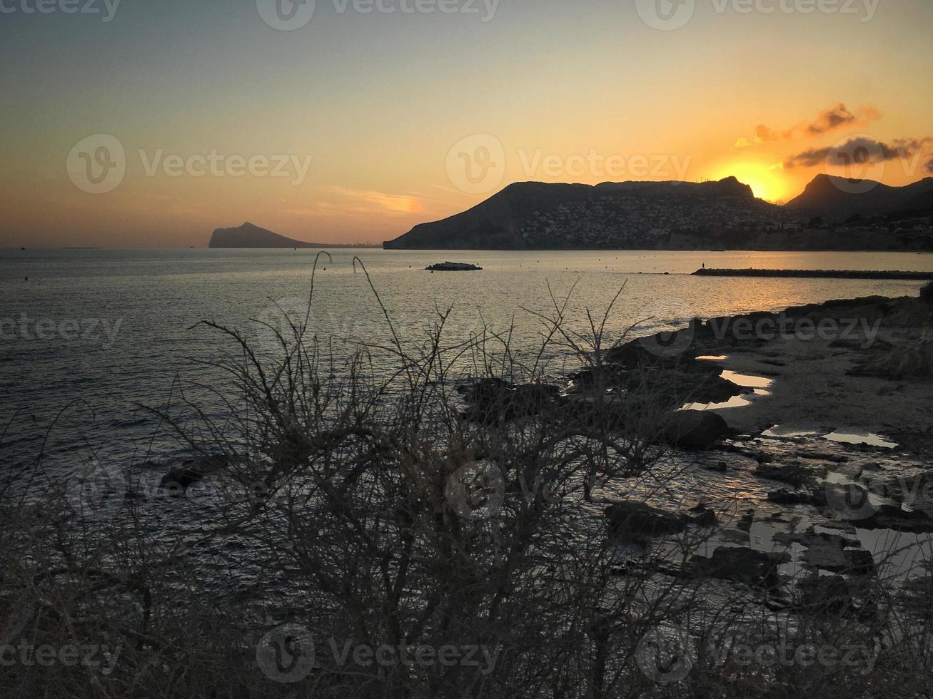 praia mediterrânea sem pessoas ao pôr do sol em calpe, alicante foto