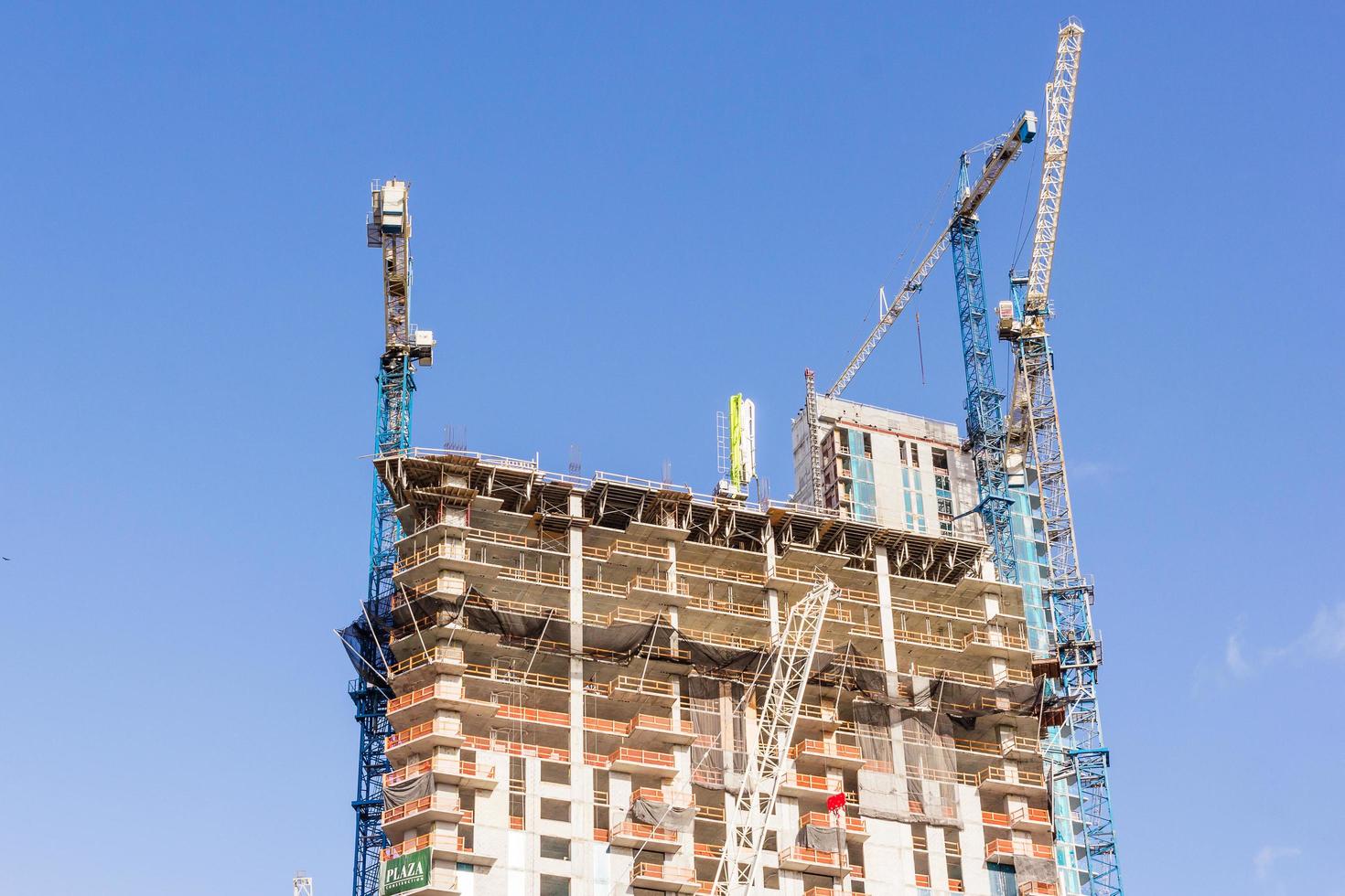 guindastes de construção industrial e edifício em um fundo de céu azul lindo foto