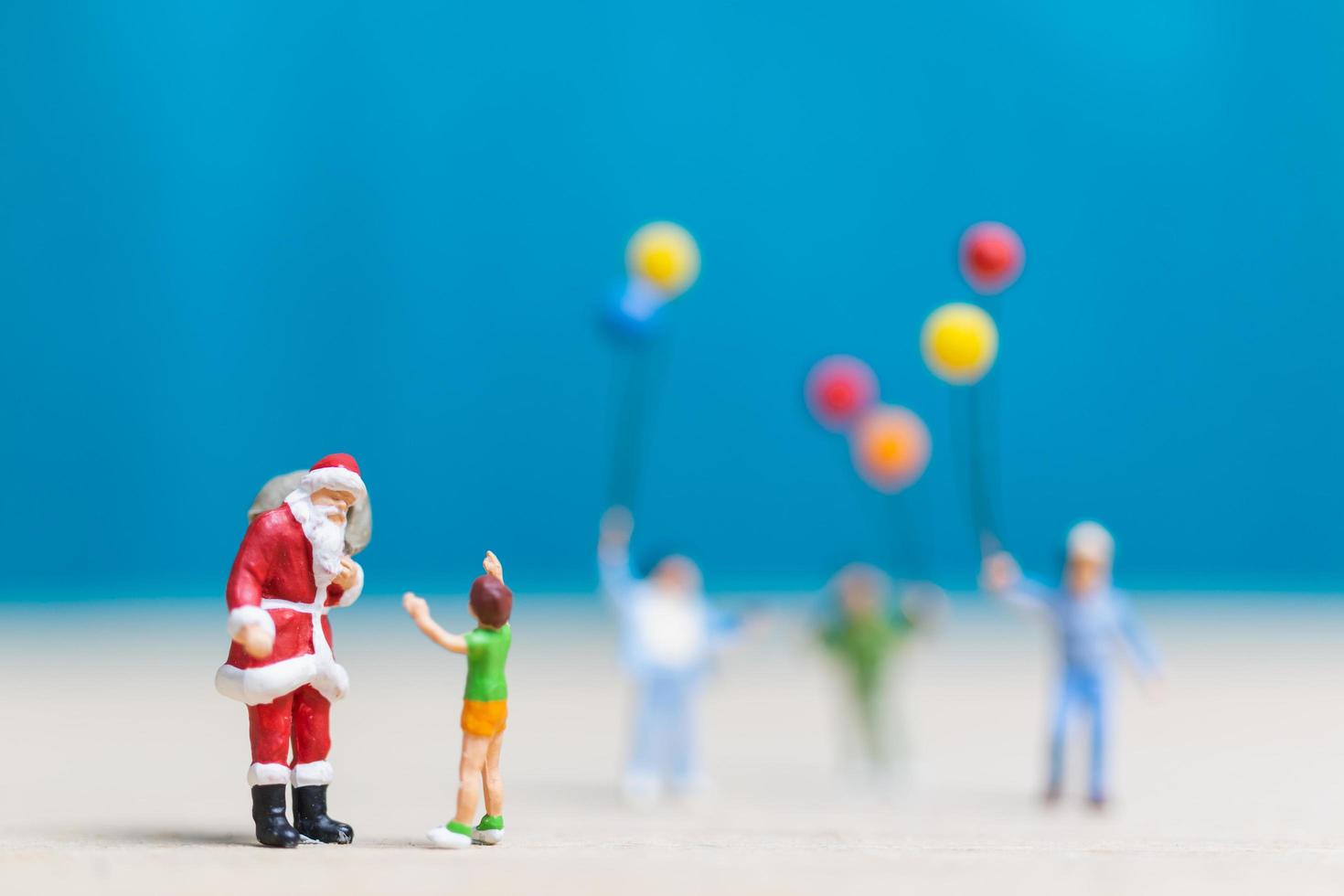 Papai Noel em miniatura e crianças segurando balões, conceito de feliz natal e feliz ano novo foto