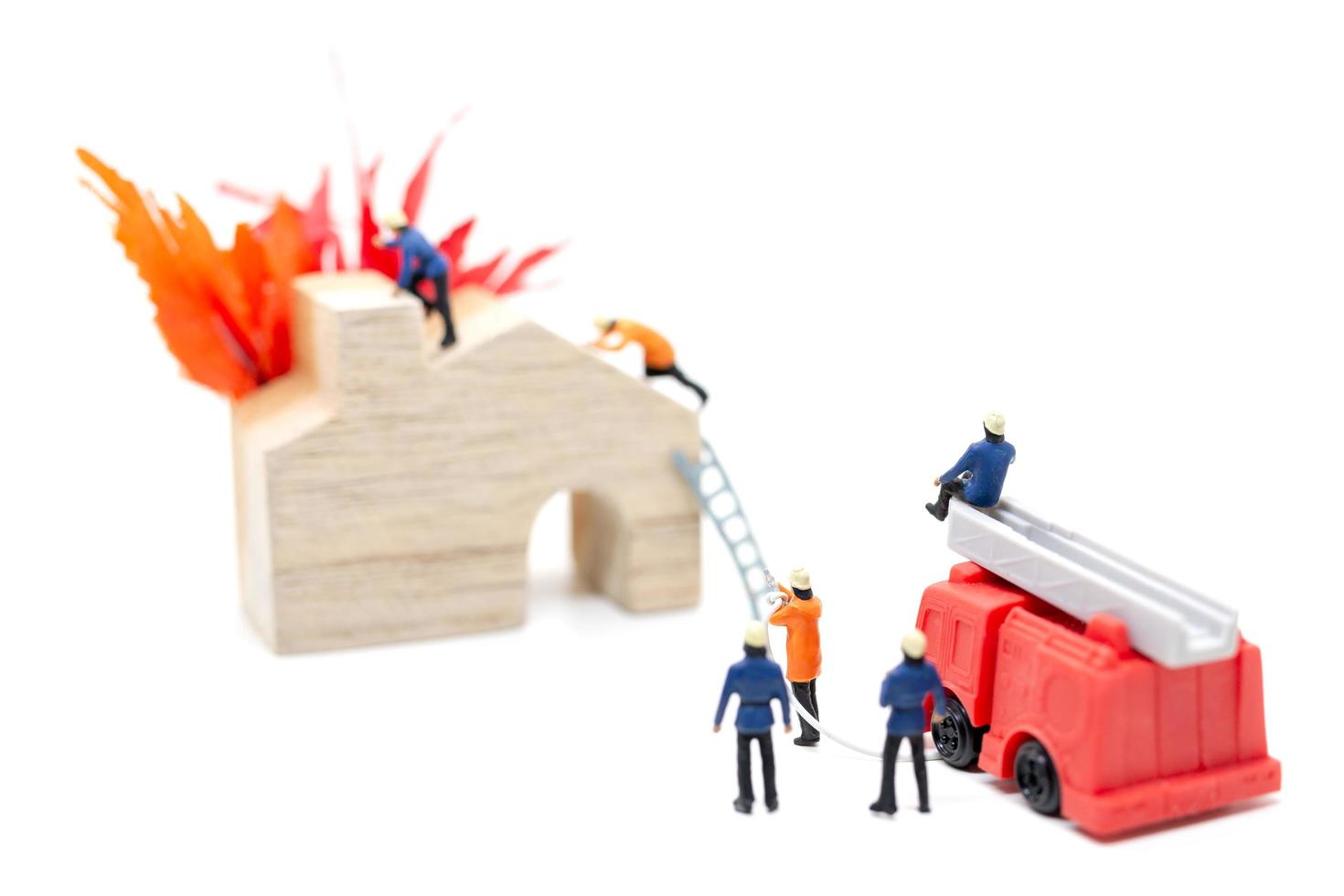 bombeiros em miniatura cuidando de um incêndio em uma casa de madeira foto