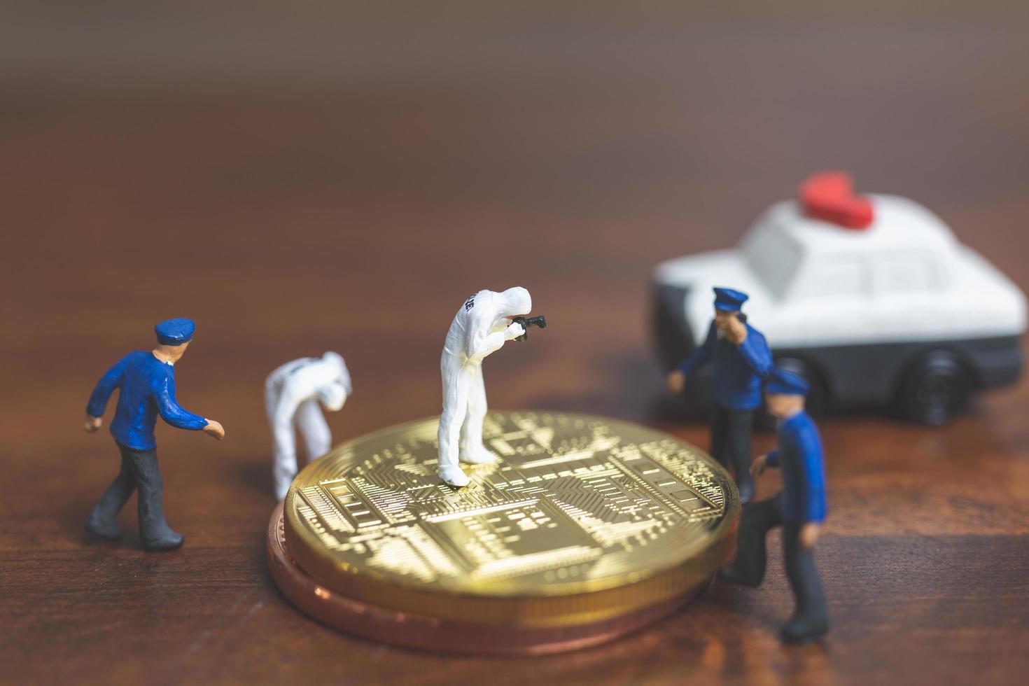 polícia em miniatura e detetives em frente à criptomoeda bitcoin, conceito de crime cibernético foto