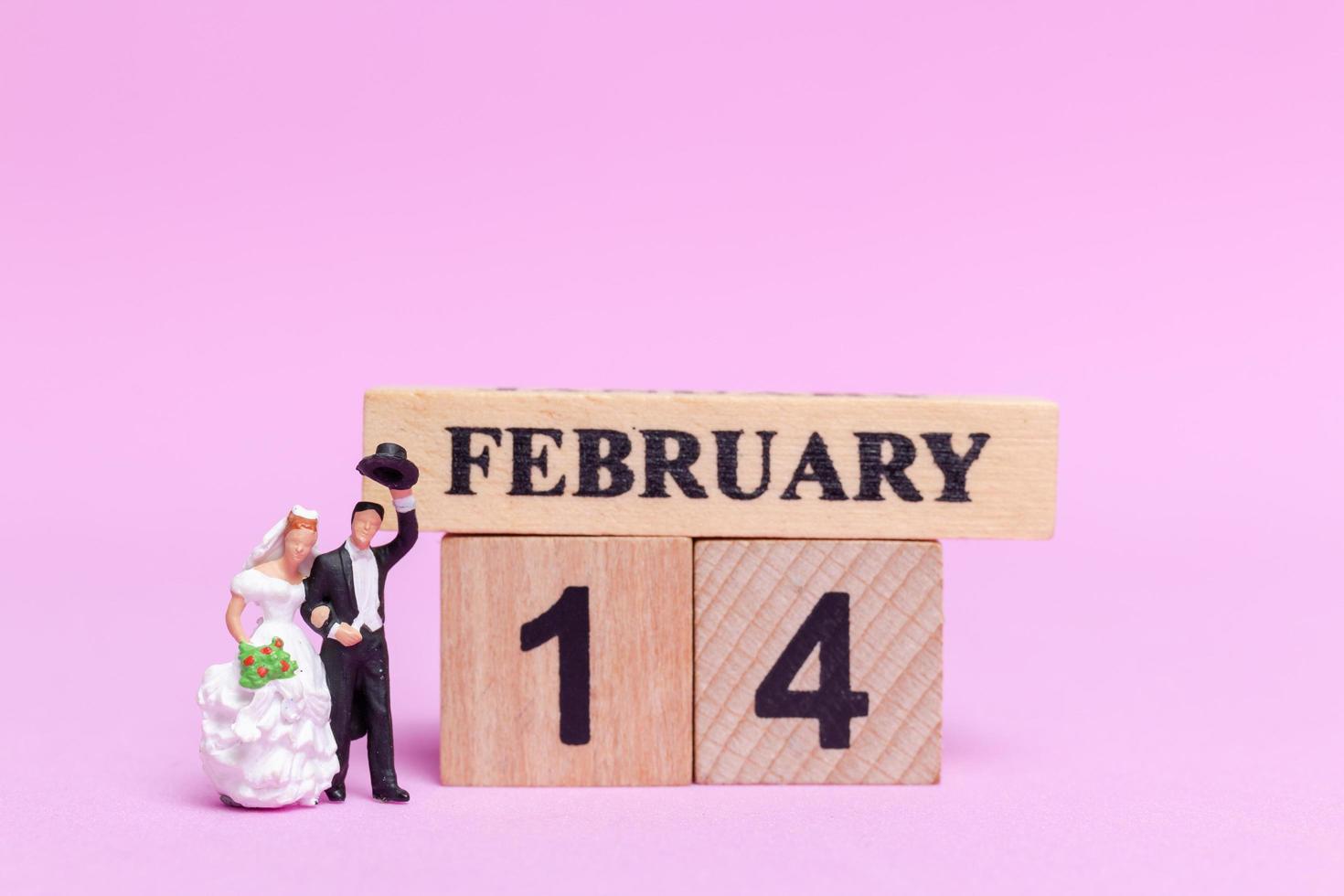 noiva e noivo em miniatura em um fundo rosa, dia dos namorados e conceito de casamento foto