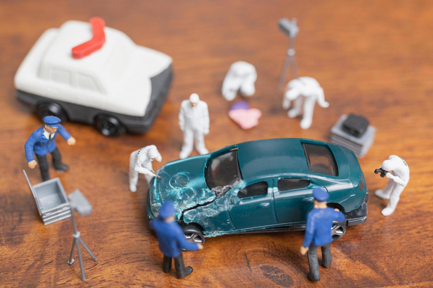 polícia em miniatura e detetive em pé ao redor de um carro, conceito de investigação da cena do crime foto