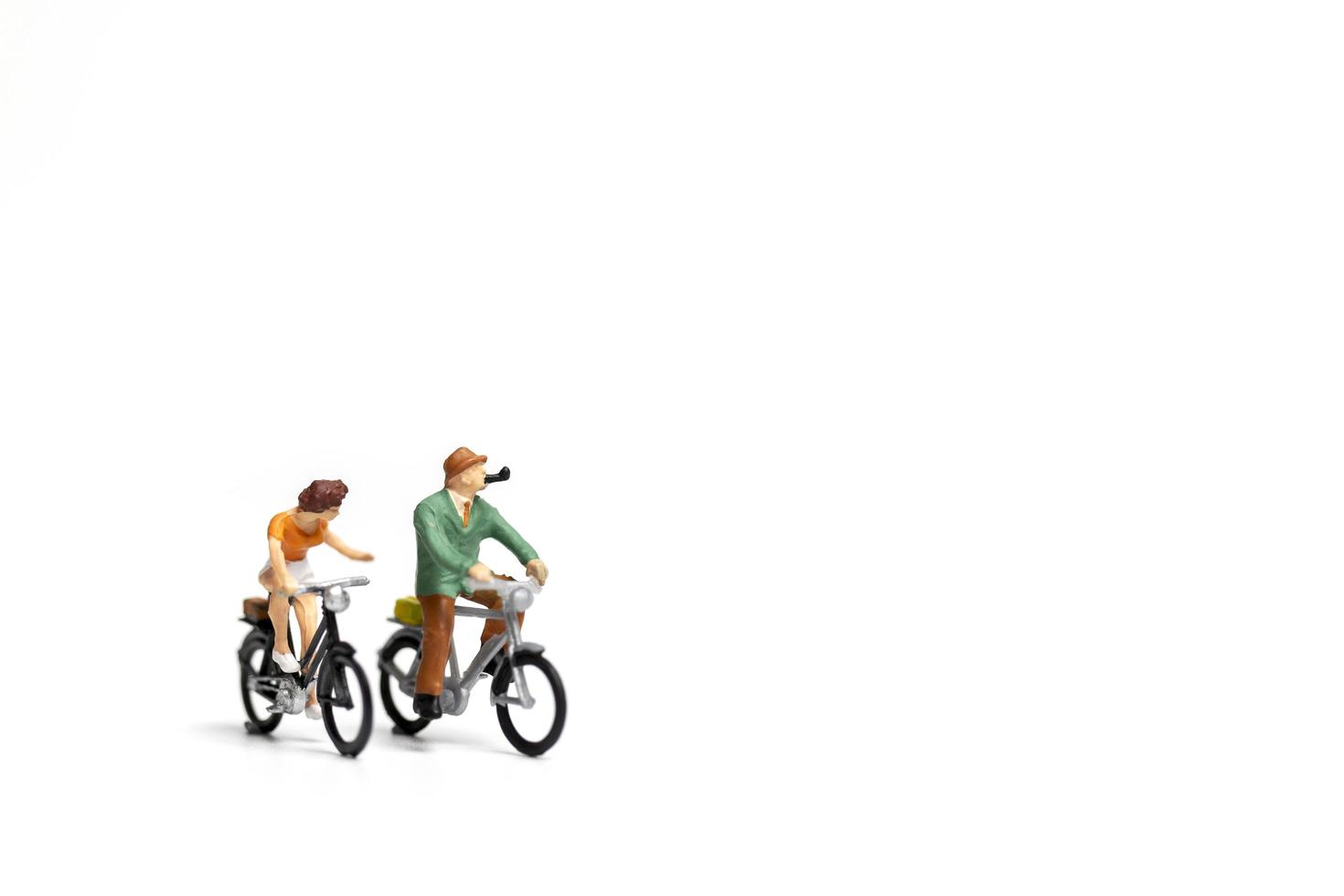 casal em miniatura andando de bicicleta em um fundo branco, conceito do dia dos namorados foto