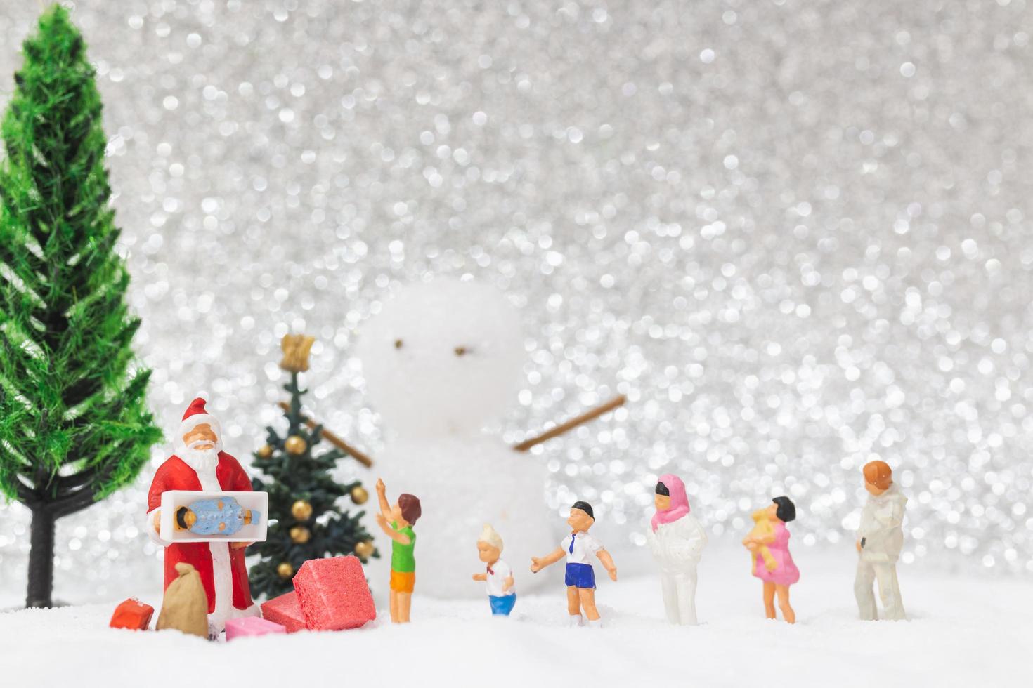 miniatura do papai noel e crianças com um fundo de neve, conceito de natal e feliz ano novo foto