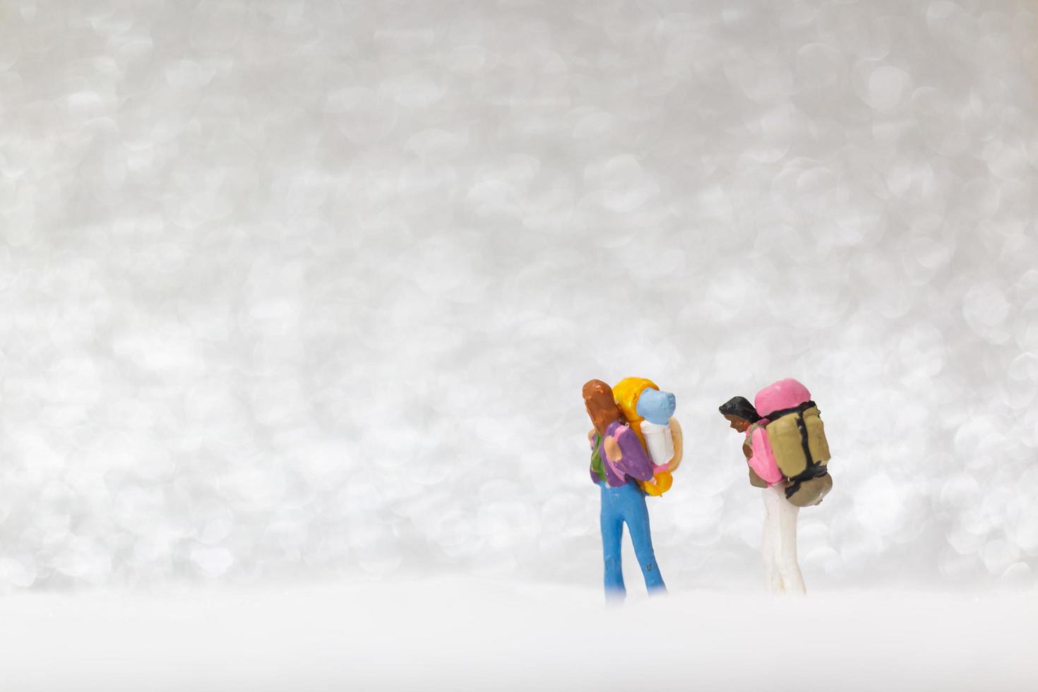 mochileiros em miniatura caminhando sobre um fundo de neve, conceito de inverno foto