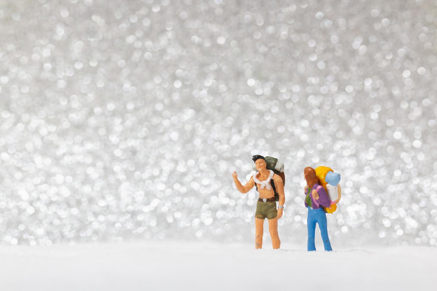 mochileiros em miniatura caminhando sobre um fundo de neve, conceito de inverno foto