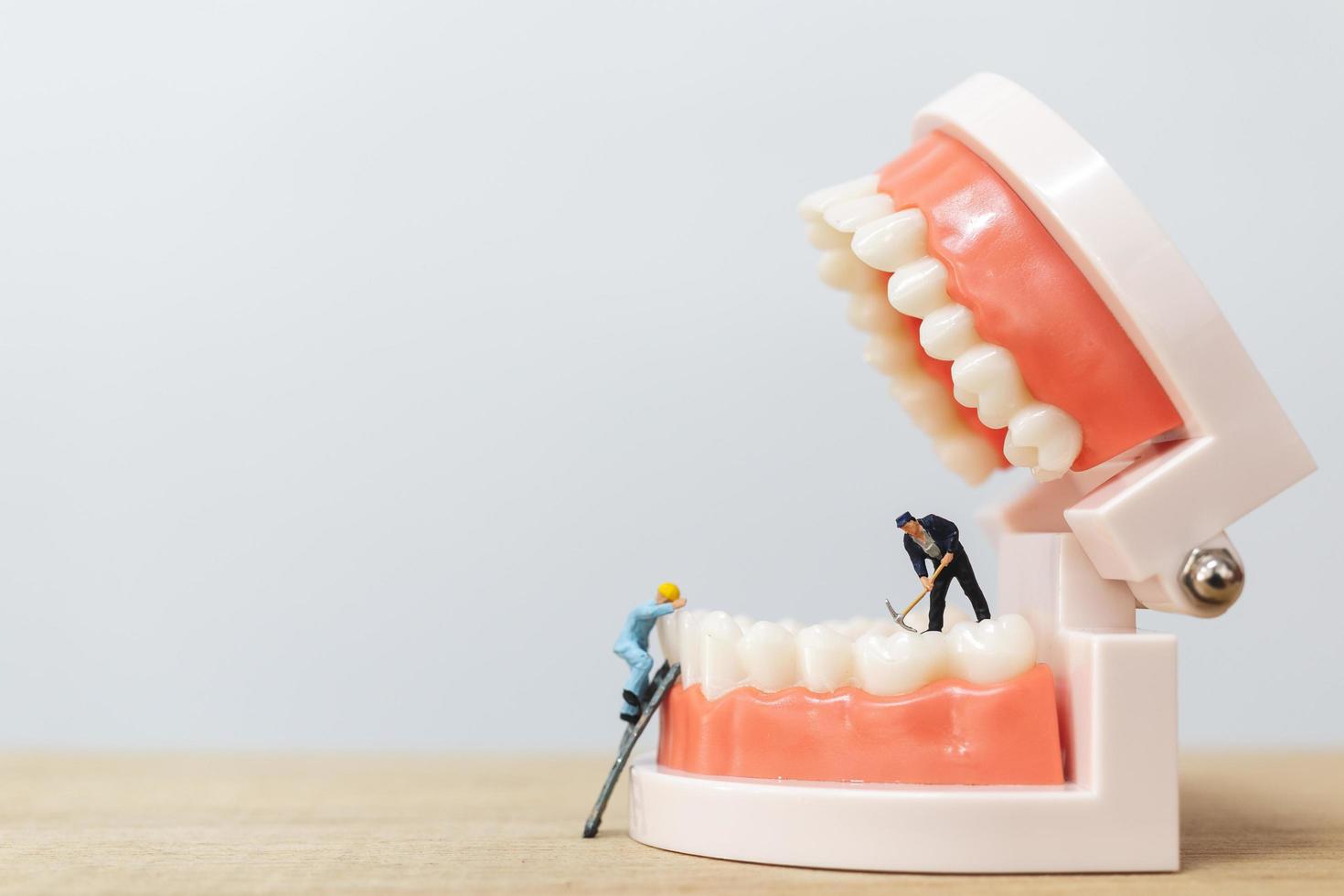 trabalhadores em miniatura consertando um dente, saúde e conceito médico foto